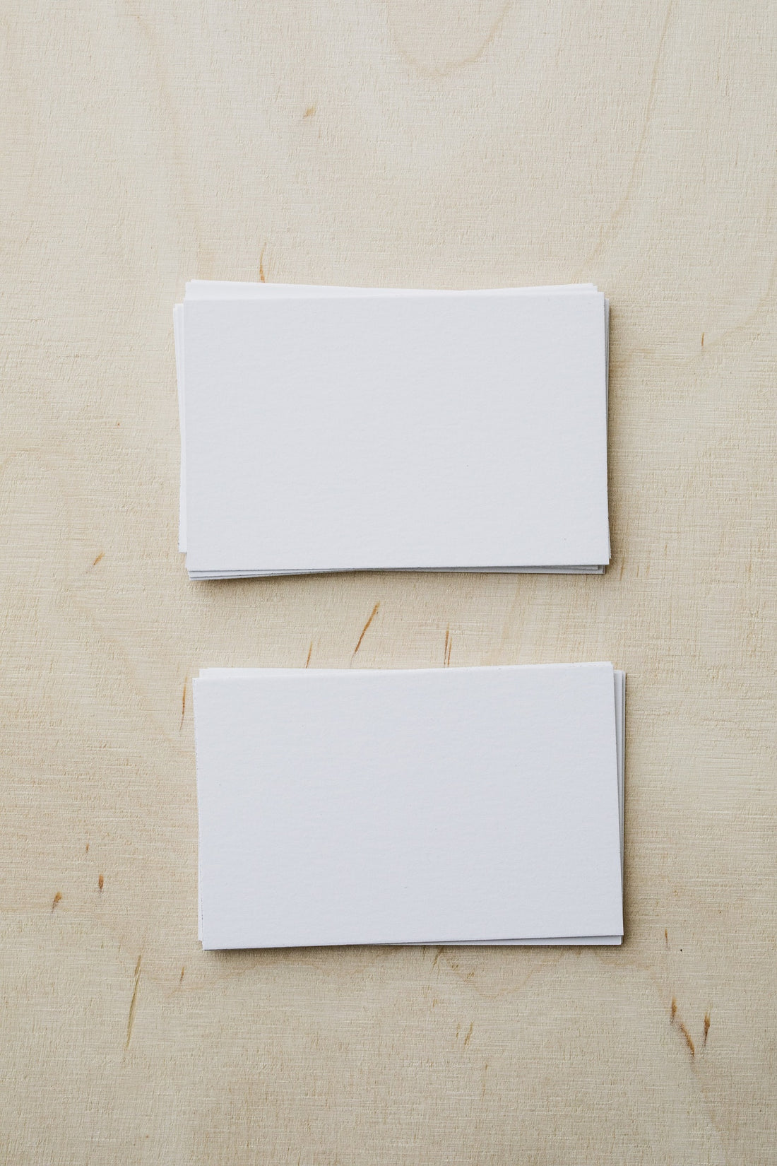 Two sheets of white paper on a cream surface.