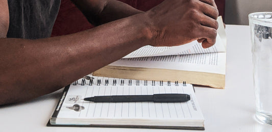  A person reading with an open notebook and pen next to them.